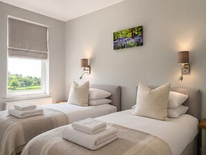 Habitación de hotel con dos camas, una ventana con vistas y lámparas fijadas a la pared.