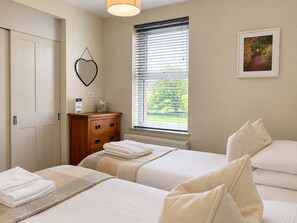 A bedroom with two beds, a dresser, a window with blinds, a radiator, and a framed picture on the wall. - Howgills House | Self-catering accommodation | Countryside location  (Sedbergh)