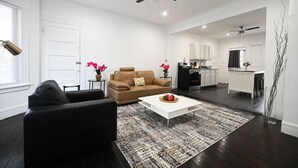 A modern living room with a sofa, coffee table, and a kitchen in the background. - ENTIRE APARTMENT RECENTLY RENOVATED 2BR (Ansonia)