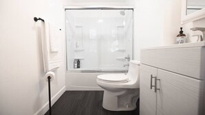 A modern bathroom with a toilet, a glass shower enclosure, a white vanity with drawers, and a towel rack. - ENTIRE APARTMENT RECENTLY RENOVATED 2BR (Ansonia)