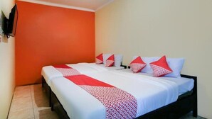 A hotel room with a large bed, orange walls, and a TV mounted on the wall. - OYO 3263 House 140 (Baturetno)