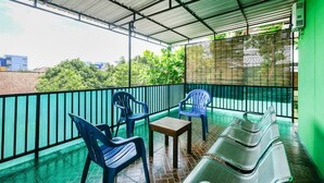 A covered balcony with blue plastic chairs, a small table, and a metal bench. - OYO 3263 House 140 (Baturetno)