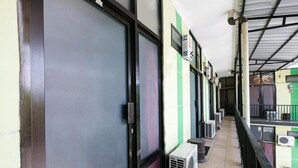 A corridor with closed doors, air conditioning units, and a tiled floor. - OYO 3263 House 140 (Baturetno)