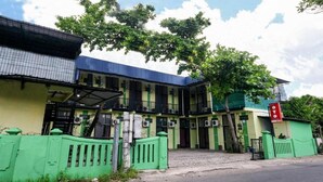 A multi-story building with a green and yellow facade, multiple air conditioning units, and a gated entrance. - OYO 3263 House 140 (Baturetno)