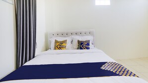 A neatly made bed with white bedding and blue accents, a grey headboard, and two pillows with yellow and black patterns. - Spot ON 3993 Zidney 2 Syariah (Salatiga)