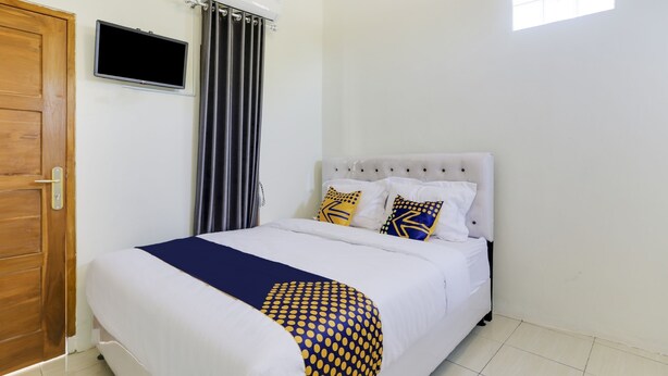 A bedroom with a bed, a television, a window, and a door. - Spot ON 3993 Zidney 2 Syariah (Salatiga)