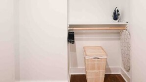 Un petit placard fermé, doté d’un plancher en bois, d’une tringle pour suspendre les vêtements et d’une boîte de rangement.