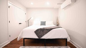 Une chambre à coucher avec un lit, une lampe de chevet et un appareil de climatisation.