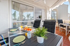Un comedor con una mesa dispuesta para dos, una planta en maceta y vistas al exterior.