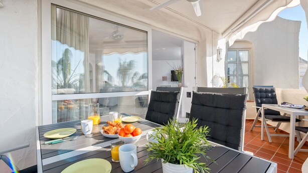 Un coin repas avec une table mise pour le petit-déjeuner, comprenant des assiettes, des couverts et un saladier de fruits.