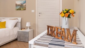 Une chambre à coucher bien rangée, avec un lit, une table de chevet, une lampe et le mot décoratif « RÊVE » posé sur le lit.