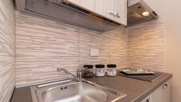 Une cuisine moderne dotée d’un évier en acier inoxydable, de meubles en bois et d’un crédence décorée.