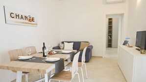 Ein moderner Essbereich mit einem Holztisch, weißen Stühlen und einem grauen Sofa. An der Wand hängt ein gerahmtes Schild mit dem Wort "CHANGE".