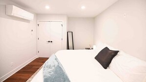 A bedroom with a bed, a bedside table, a mirror, and a wardrobe. - Unit 102 · Near Yale and Downtown Newly Renovated (New Haven)