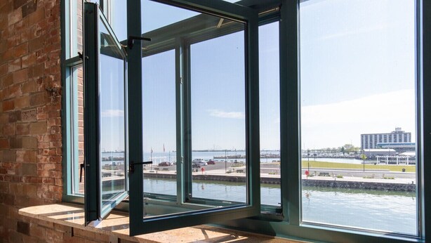 A room with large windows overlooking a marina and a bridge.