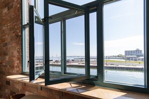Una habitación con ventanas amplias que dan a un puerto deportivo y un puente.