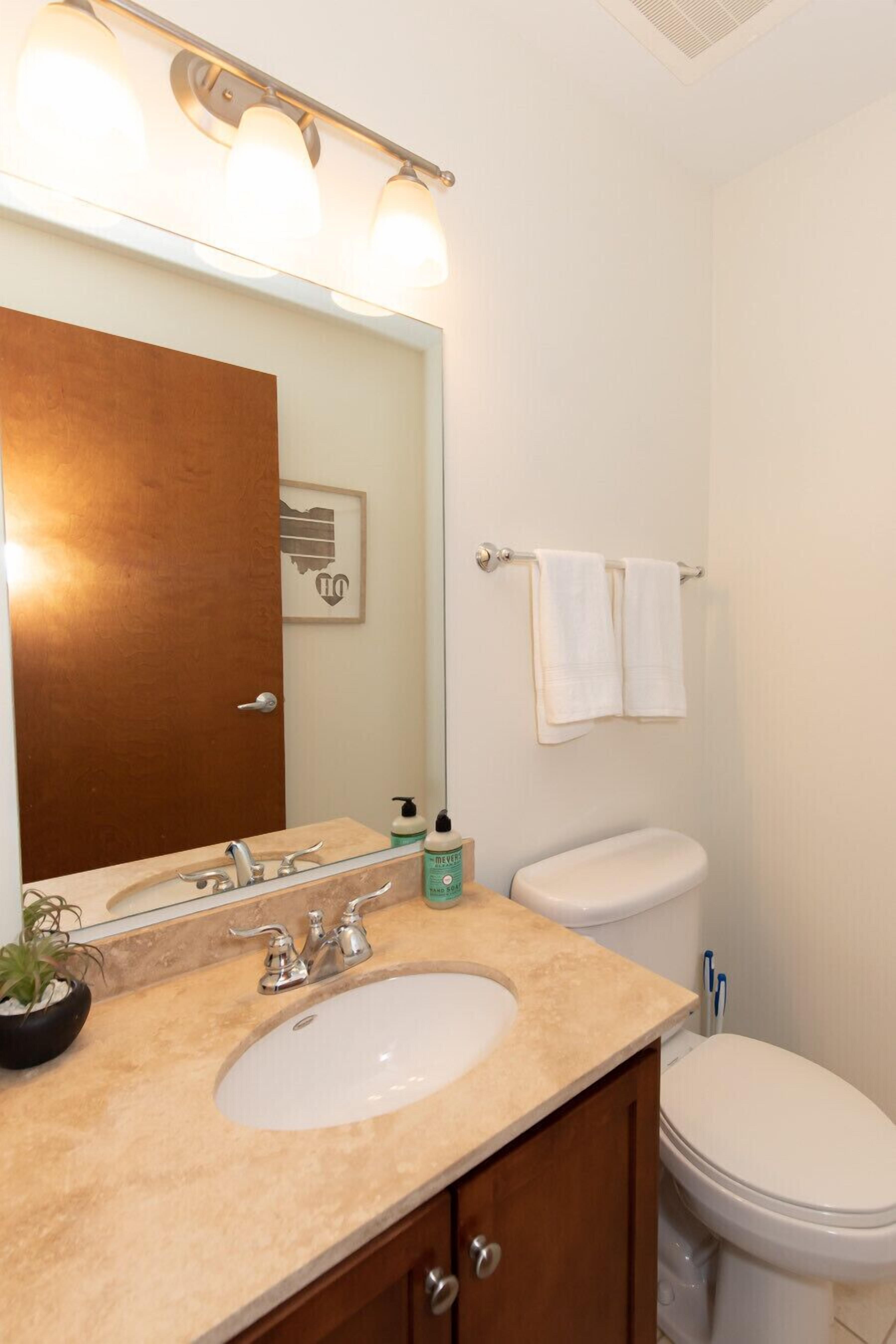 Une salle de bain équipée d’un lavabo, d’un miroir, de toilettes et d’un porte-serviettes.