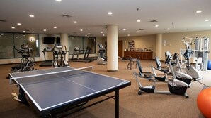 A fitness center with exercise equipment, a ping pong table, and a reception area.