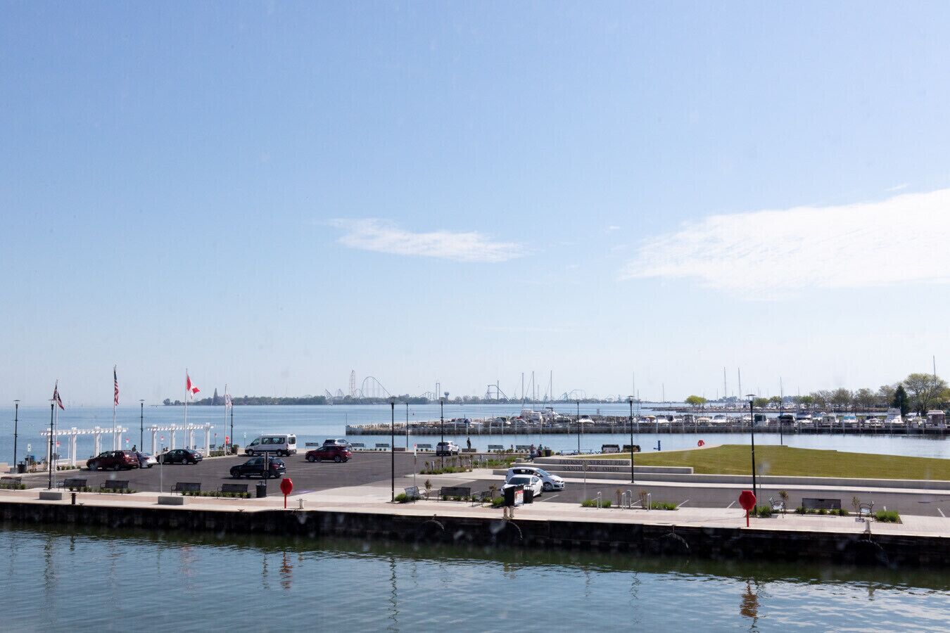 Ein Parkplatz am Wasser mit Autos und einem Yachthafen im Hintergrund.
