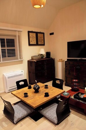 A dining area with a wooden table, black chairs, a tea set, and a television on the wall. - Wabi Sabi B&B - a Japanese Sleep Oasis in Belgium (Peer)