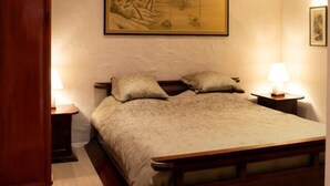 A bedroom with a large bed, wooden headboard, a painting on the wall, and a nightstand with a lamp. - Wabi Sabi B&B - a Japanese Sleep Oasis in Belgium (Peer)