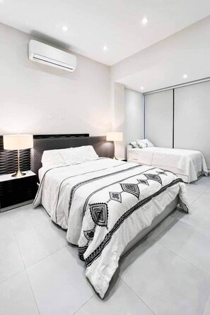 Une chambre d’hôtel moderne avec un grand lit, des tables de chevet, un bureau et une armoire.