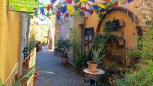 A narrow cobblestone alley with a sign reading "ÉLUE LA PLUS BELLE RUE FLEURIE DU VILLAGE". - Villa Mathis (Mouans-Sartoux)