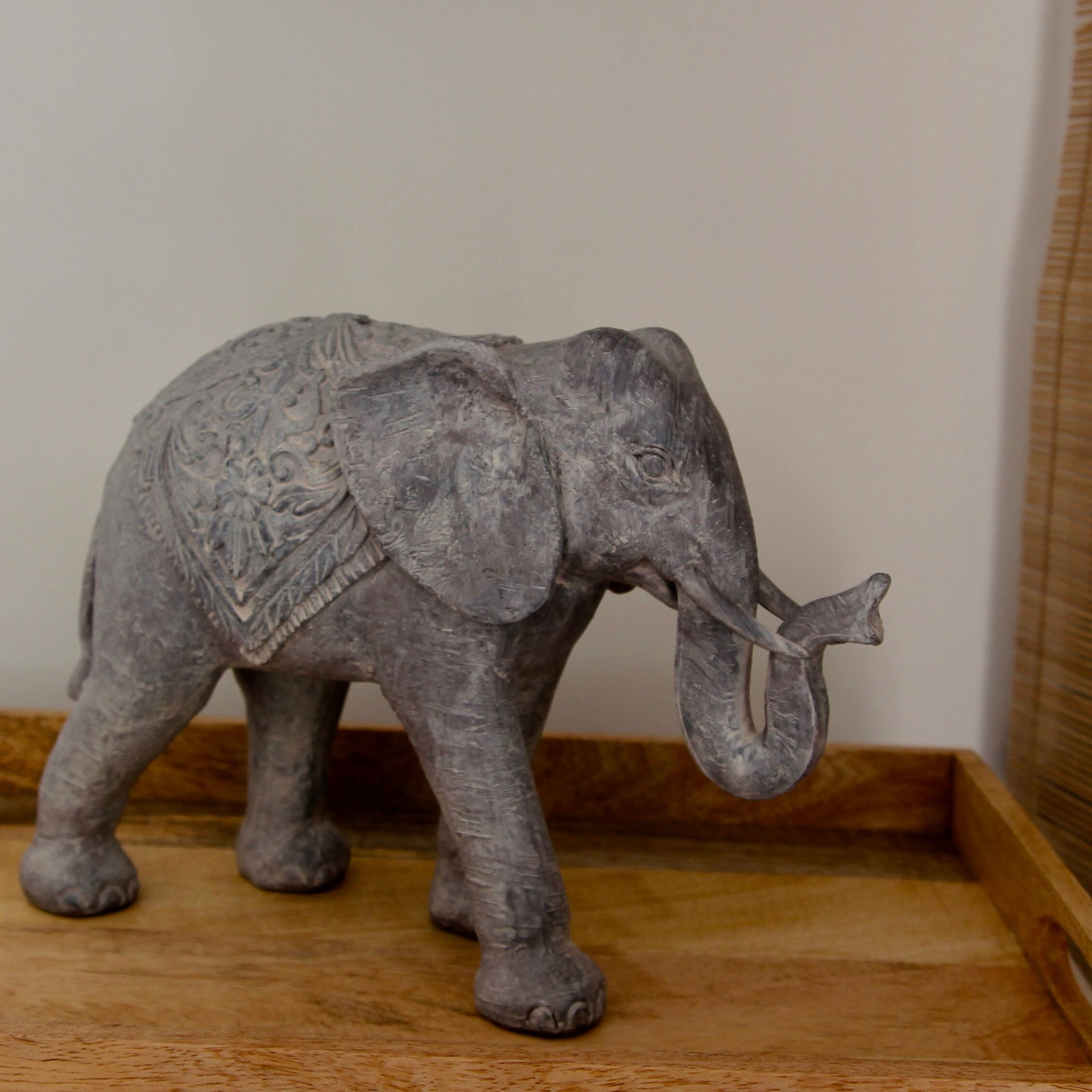 Una piccola scultura di elefante su un ripiano di legno.