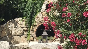 A stone bench with a lantern and potted plant in a garden with a stone wall and flowering plants. - Villa Mathis (Mouans-Sartoux)