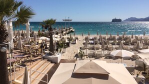 A beachside resort with sun loungers, umbrellas, and a view of the sea. - Villa Mathis (Mouans-Sartoux)