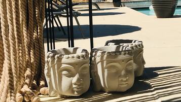 Outdoor stone planters with a classical design, a rope barrier, and a pool area in the background.