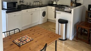 Una cocina compacta con armarios blancos, microondas, lavadora, estufa y pileta.