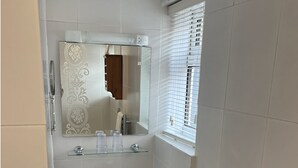 Un baño con lavamanos blanco, espejo y perchero.