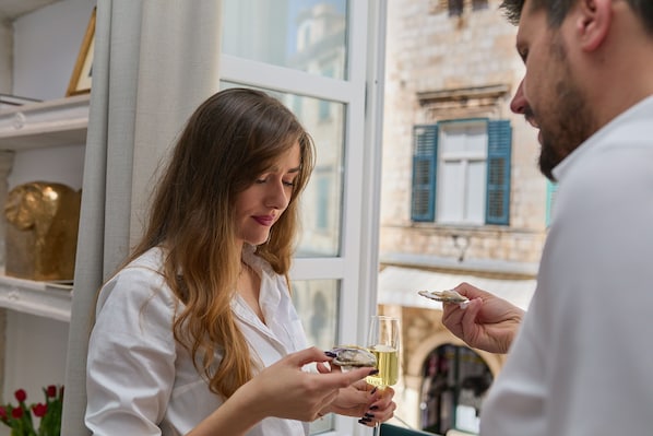 A person holding a glass of champagne and an oyster.
