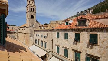 A historic building with a tower, terracotta tiled roofs, and traditional shutters.