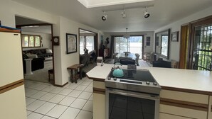 A kitchen with a central island, an oven, and a dining area with a table and chairs. - Beautiful Lake Front Property  (Bayview)