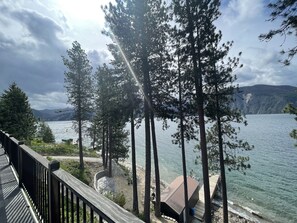 A lakeside view with tall trees, a wooden deck, and a small building near the water. - Beautiful Lake Front Property  (Bayview)