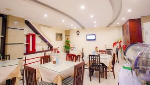 A hotel dining area with round tables, chairs, a TV, and a staircase. - Hanoi Palace Hotel (Hanoi)