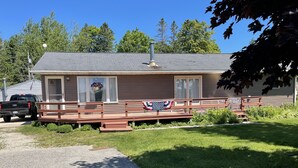 A single-story house with a porch, a flag, and a truck parked in front.