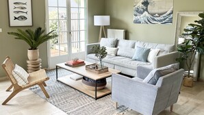 Een woonkamer met een bank, fauteuil, bijzettafeltje en decoratieve objecten.