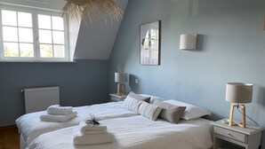 Een slaapkamer met een groot bed, twee nachtkastjes met lampen, een radiator en een raam met uitzicht.