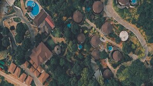 Una vista aerea di un resort con diversi edifici a tetti curvi, una piscina e sentieri sinuosi.
