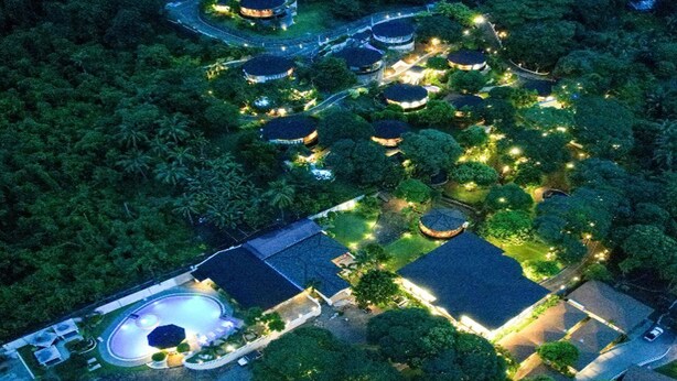 Una vista aerea di un resort con diversi edifici circolari, una piscina e sentieri ben illuminati.