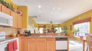 Una cocina con armarios de madera, un microondas blanco, una estufa y un lavavajillas.