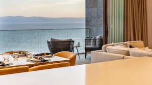 Un comedor con vistas al mar, un balcón con vistas y una zona de estar con sofá y sillones.