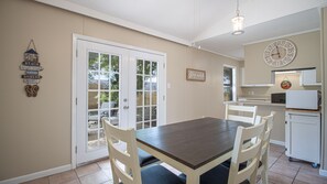 A dining area with a table and chairs, a kitchen with cabinets and appliances, and a door leading outside.