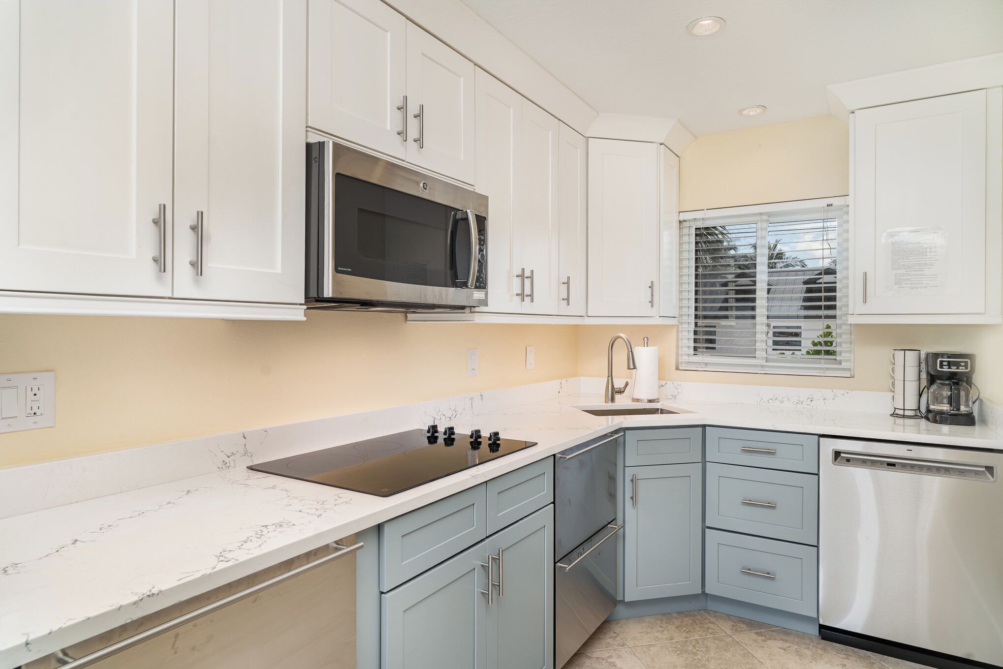 A modern kitchen with white cabinets, a stainless steel microwave, a sink, and a dishwasher.