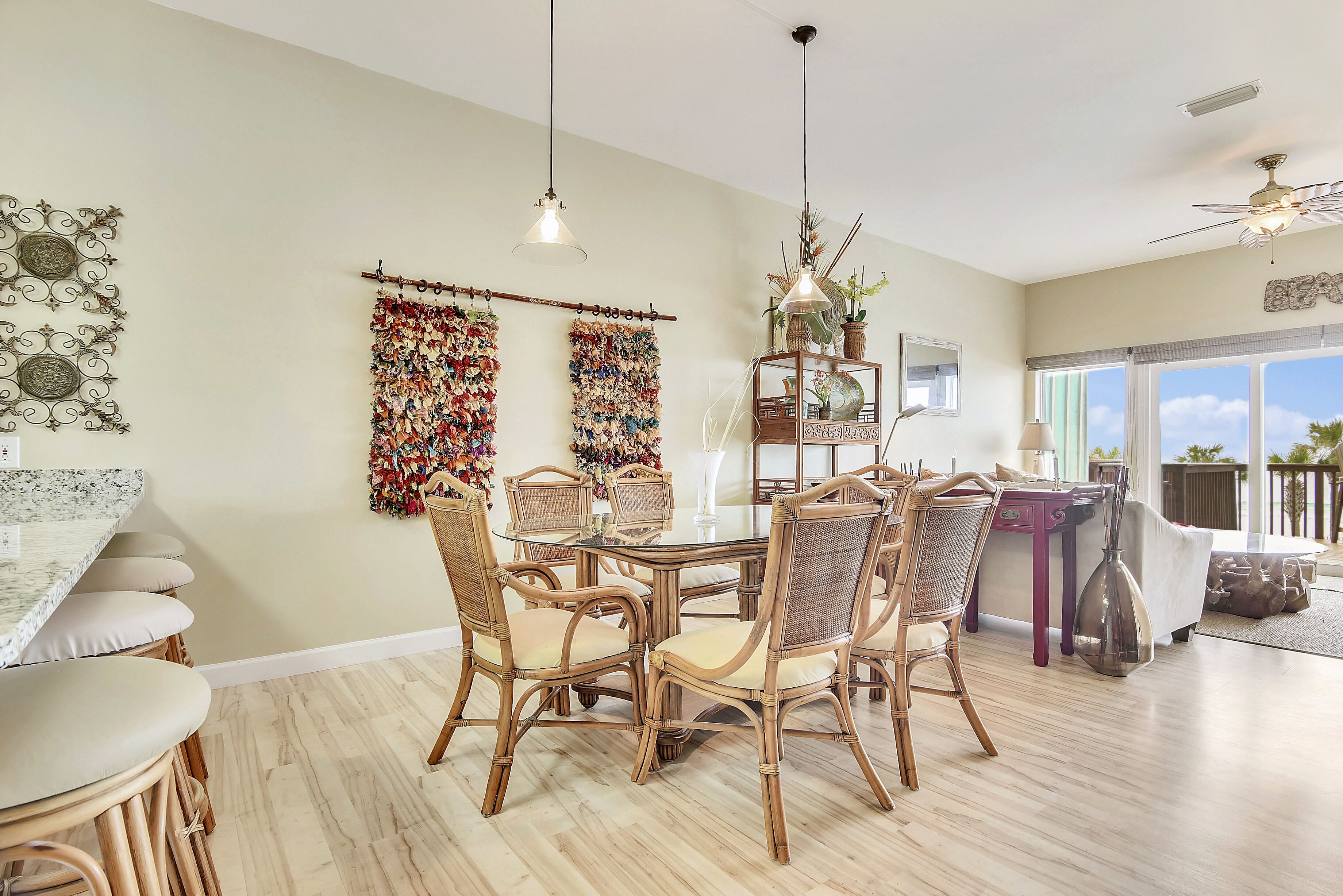 A dining area with a round table, wicker chairs, and a ceiling fan.