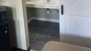 A bathroom with a white sink, a mirror, and a towel rack. - I-26 Inn (Johnson City)