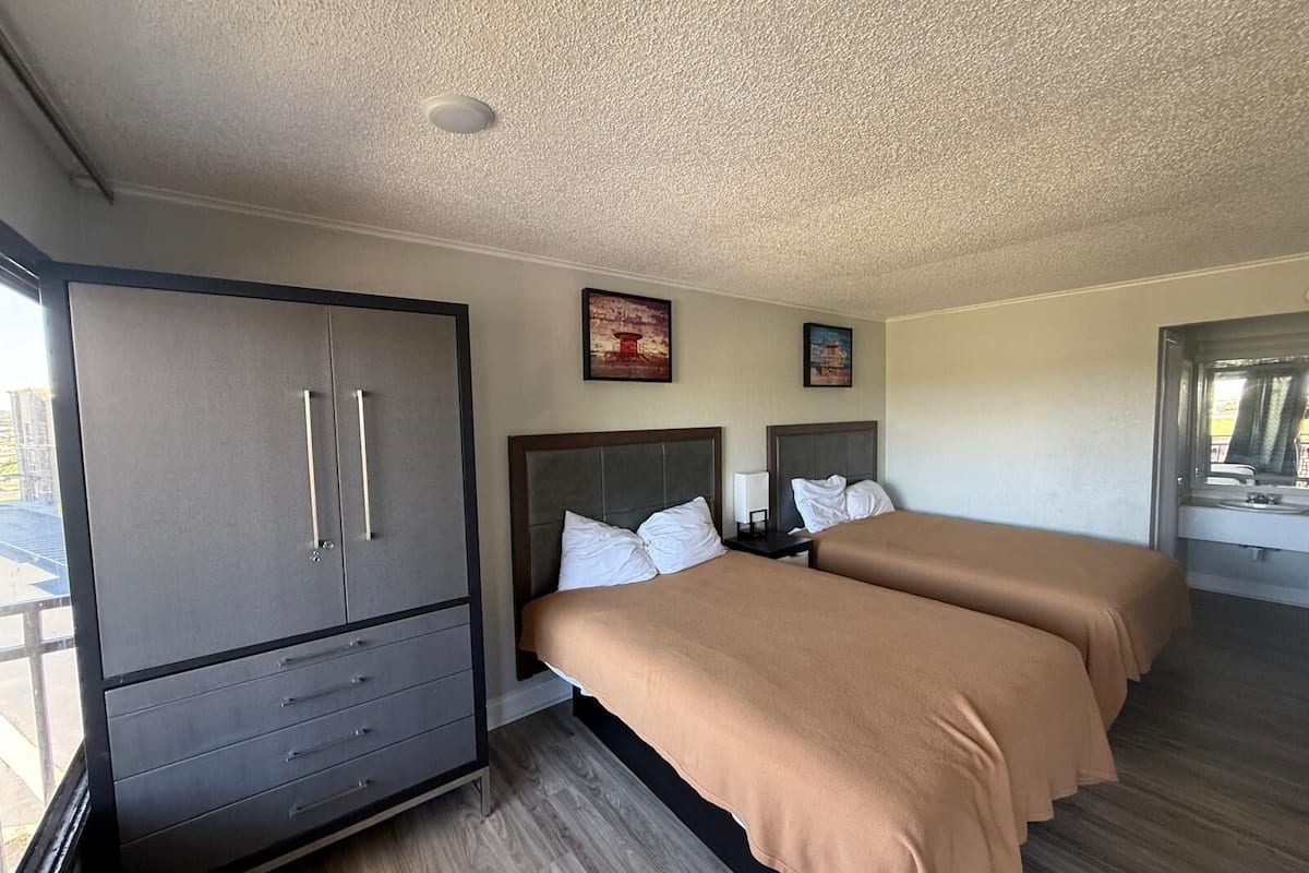 A hotel room with two beds, a wardrobe, and a window with a view.